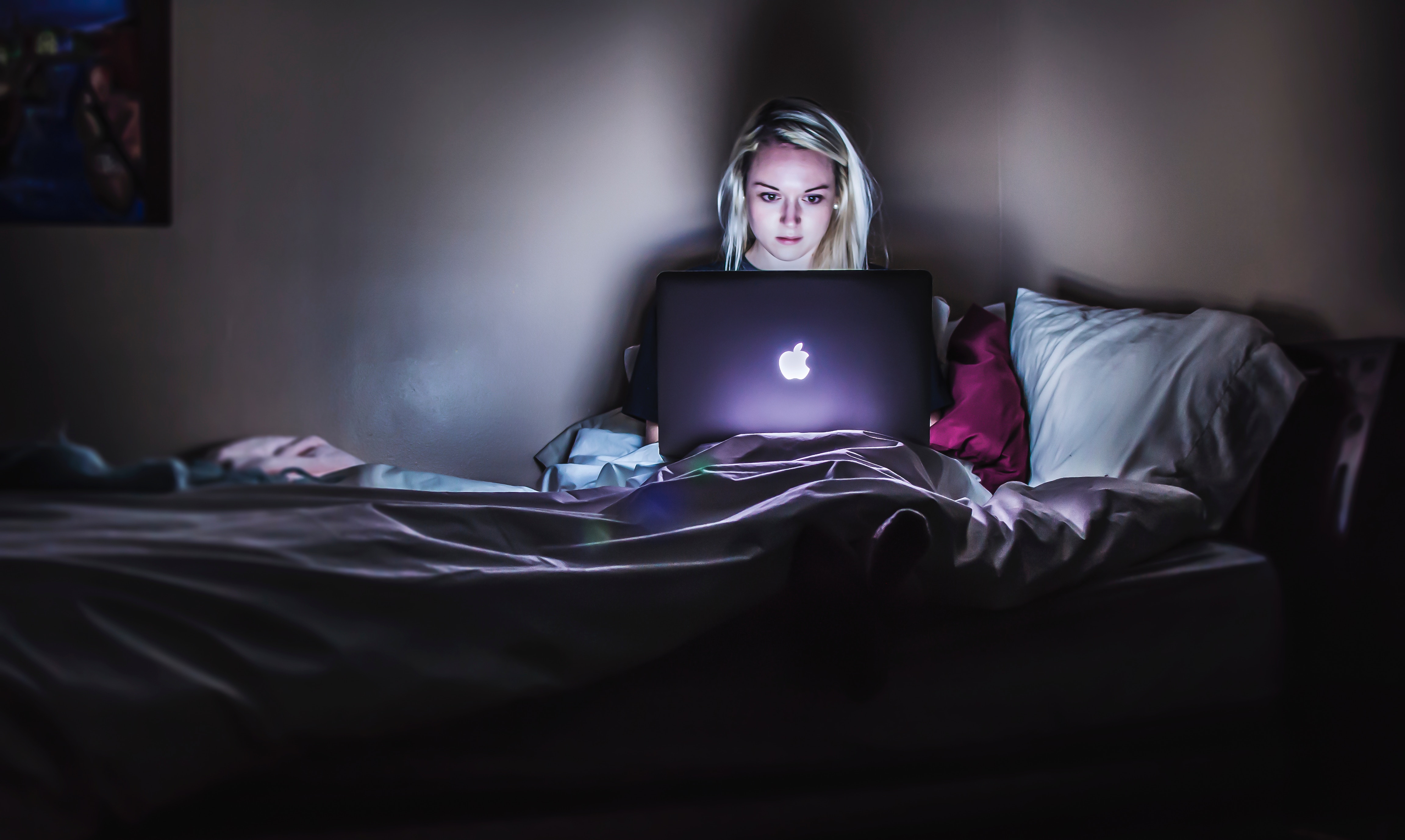 woman sitting on hostel bed with MacBook on lap