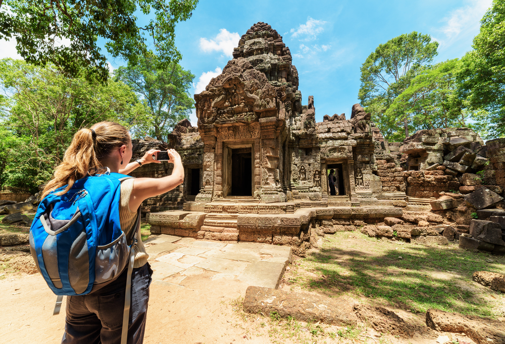 woman taking a photo of a temple in cambodia