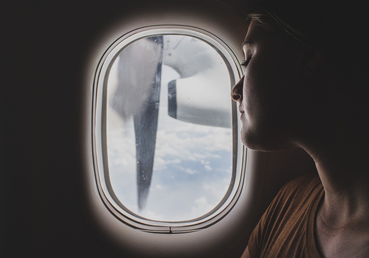 woman looking out of the window during her long haul flight woman looking out of the window during her long haul flight