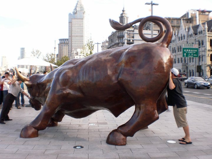 a man with his head at the butt of a statue of a bull