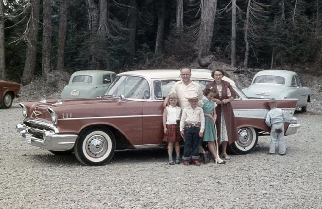 funny vacation photo of a family standing by a car