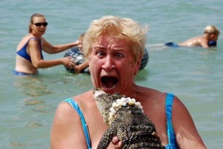 funny vacation photo of a woamn holding a small crocodile