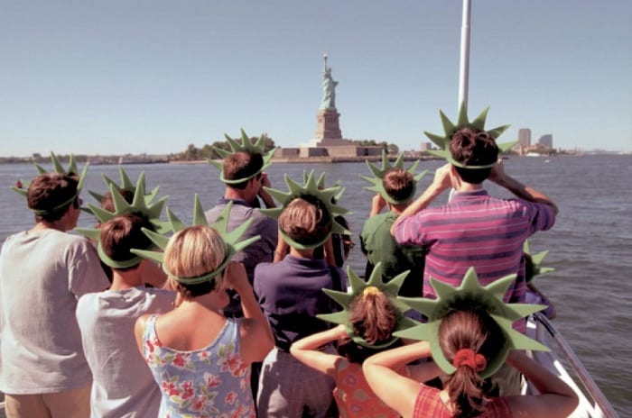 tourists on a boat going to see the statue of liberty wearing matching hats