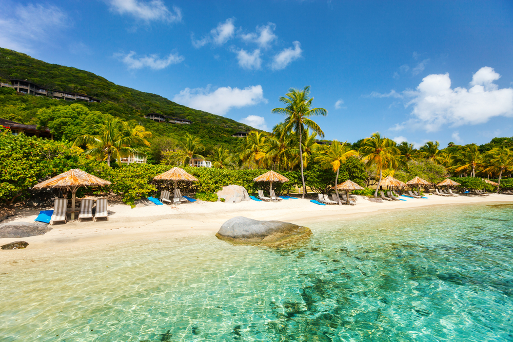 Beautiful tropical beach with palm trees, white sand, turquoise ocean water and blue sky at British Virgin Islands in Caribbean