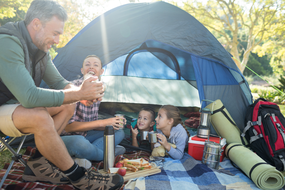 Family,Interacting,While,Having,Snacks,Outside,The,Tent,At,Campsite